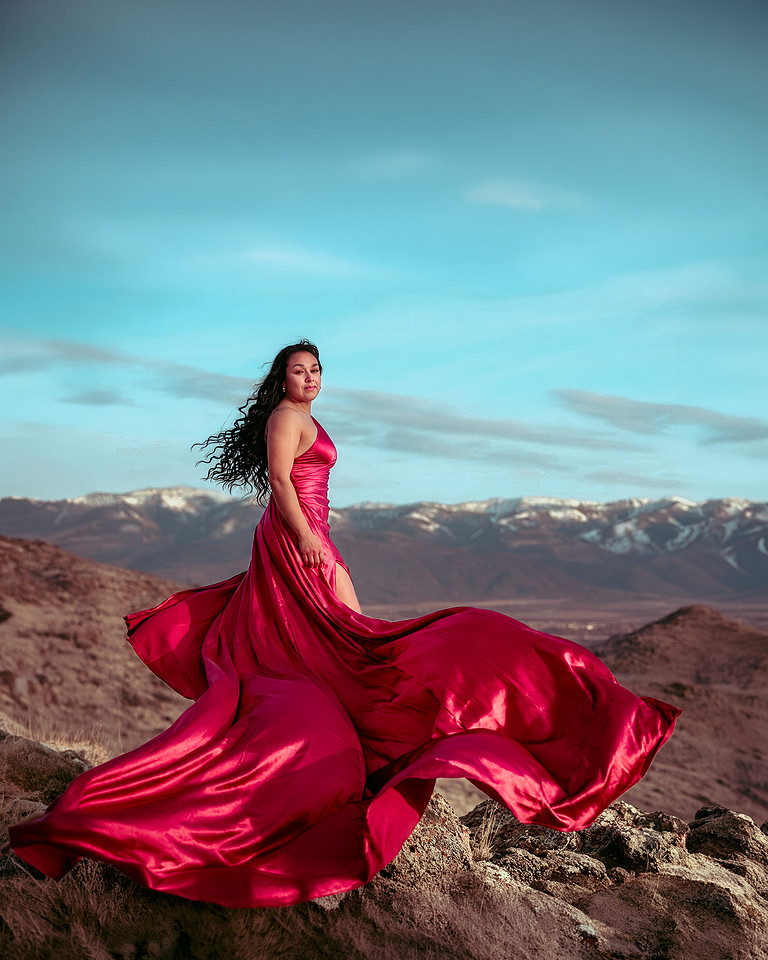 A woman in a flowing red dress photographed in the Utah landscape